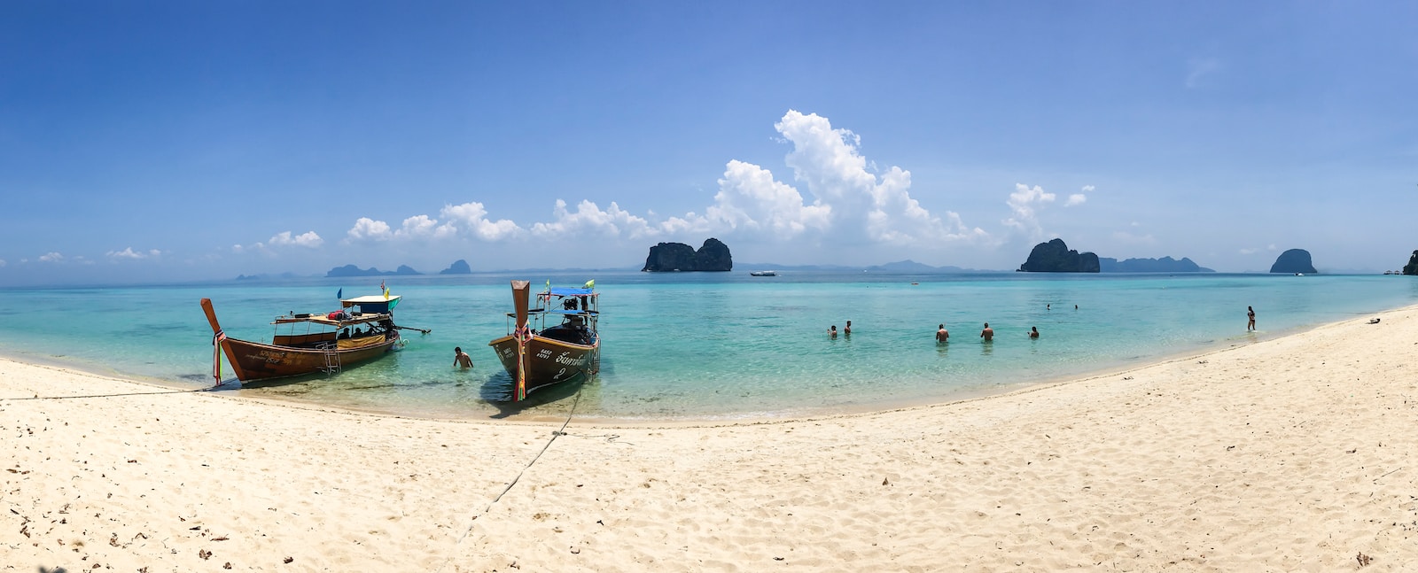 people on beach beside two brown boats during daytime Koh Lanta
